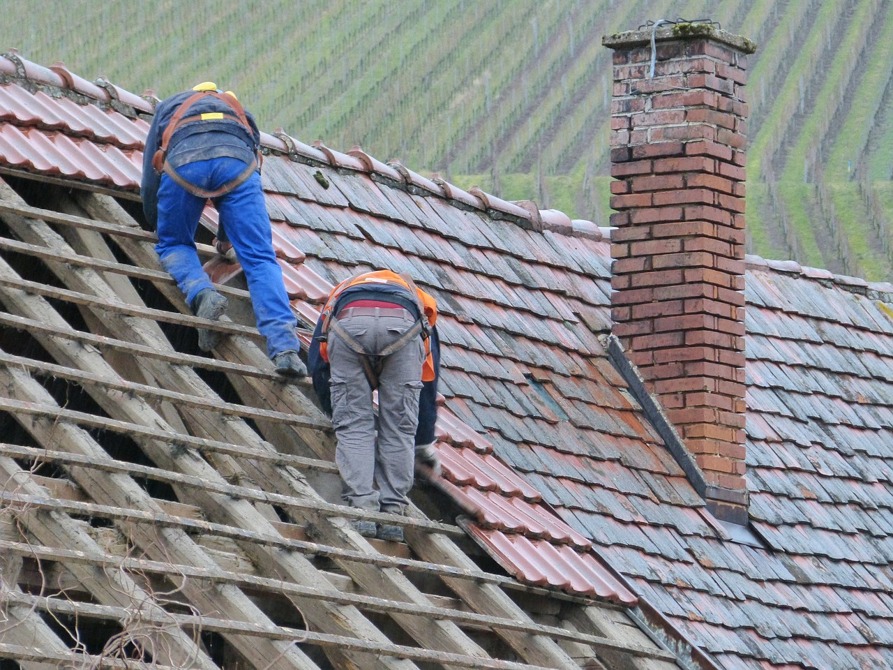 Two men working on a tiled roof in Burnaby while performing asbestos abatement.